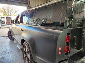 Landrover Defender 130, rear/side view, showing a black satin wrap
