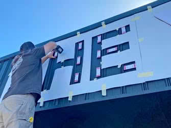 Worker installing signage to a building, closeup, outside on a sunny day